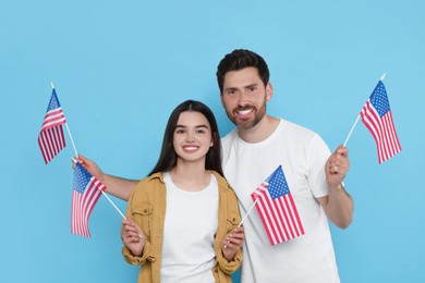 Photo of 4th of July - Independence Day of USA. Happy man and his daughter with American flags on light blue background