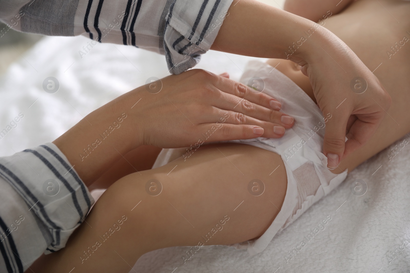 Photo of Mother changing baby's diaper on table at home, closeup