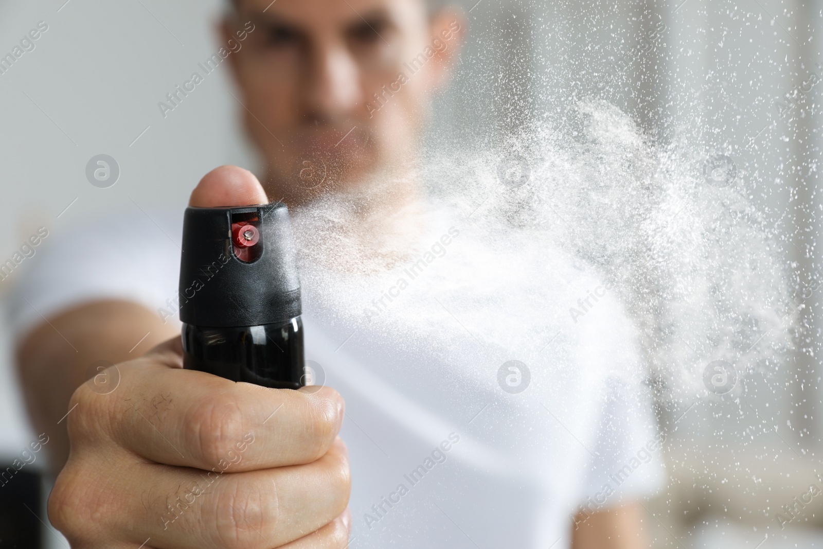 Image of Man using pepper spray at home, focus on hand