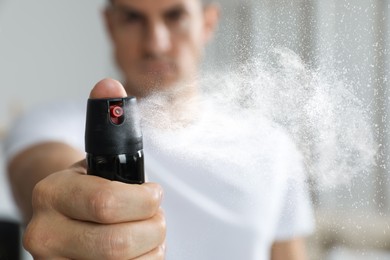 Image of Man using pepper spray at home, focus on hand