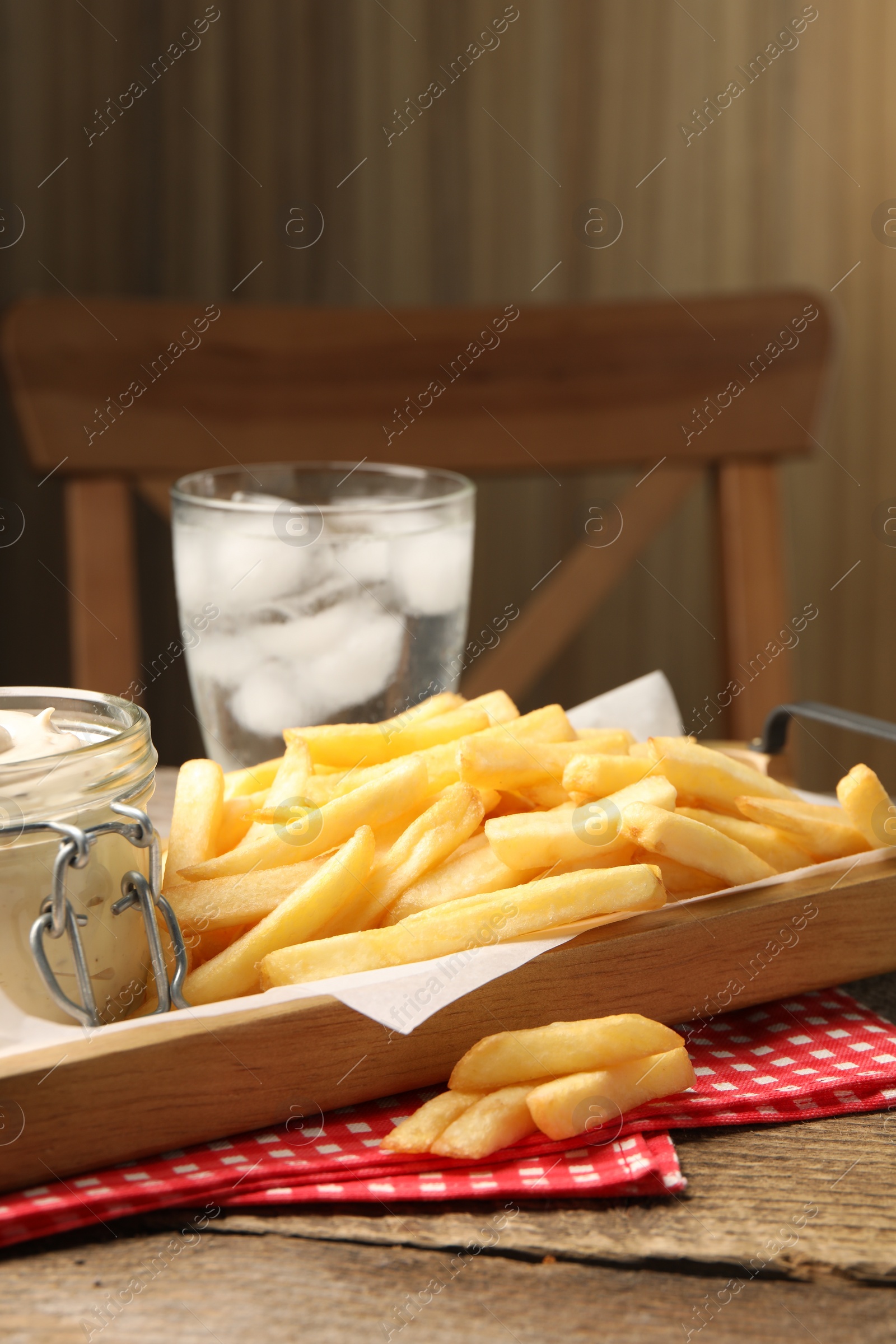Photo of Delicious french fries served with sauce on wooden table, closeup