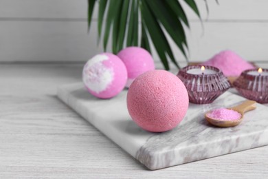 Beautiful composition with aromatic bath bombs on white wooden table, space for text