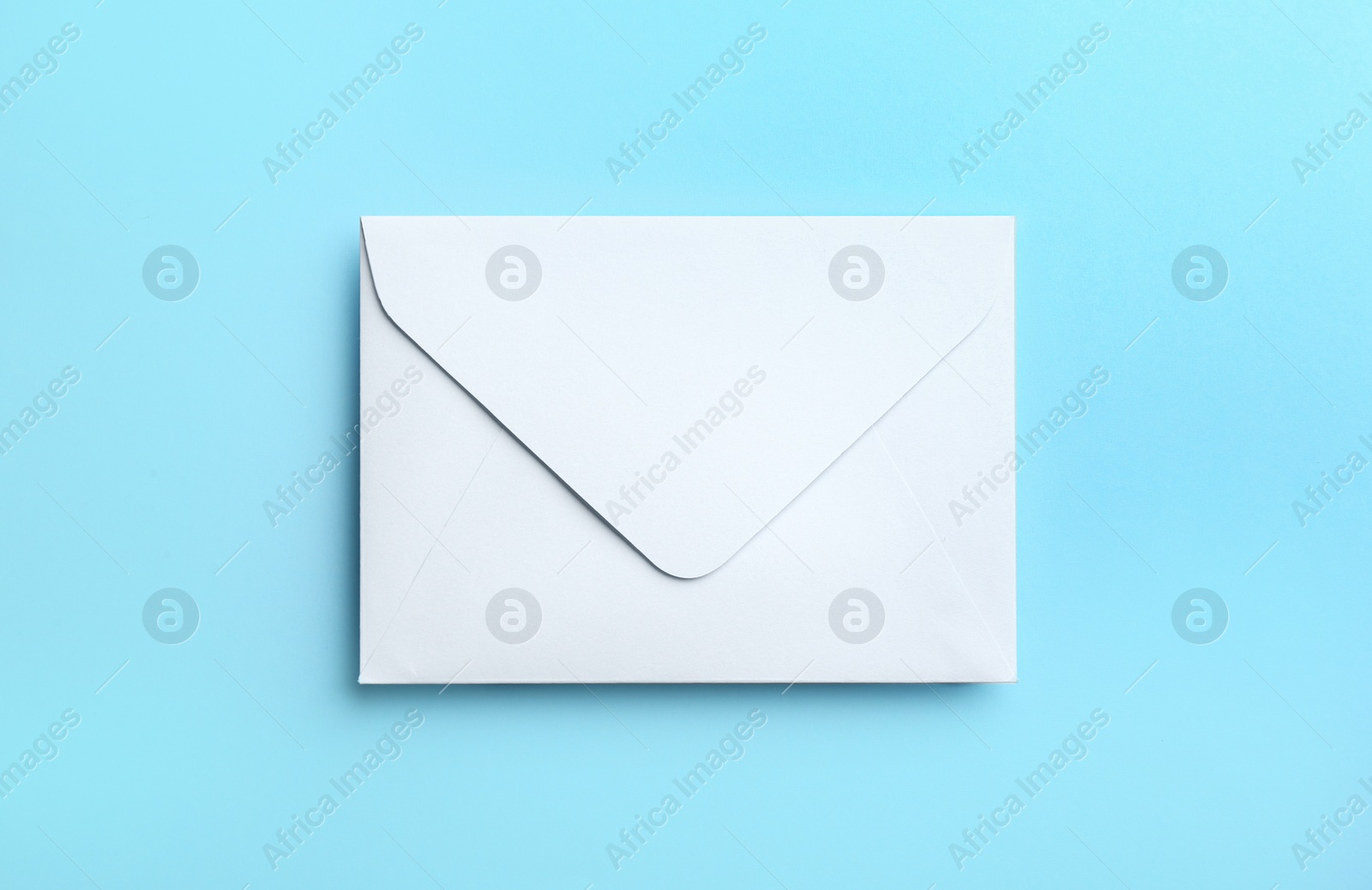 Photo of White paper envelope on light blue background, top view