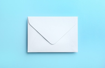 Photo of White paper envelope on light blue background, top view