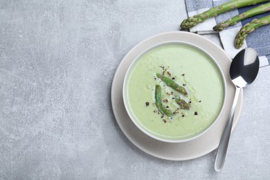 Photo of Delicious asparagus soup served on light grey table, flat lay. Space for text