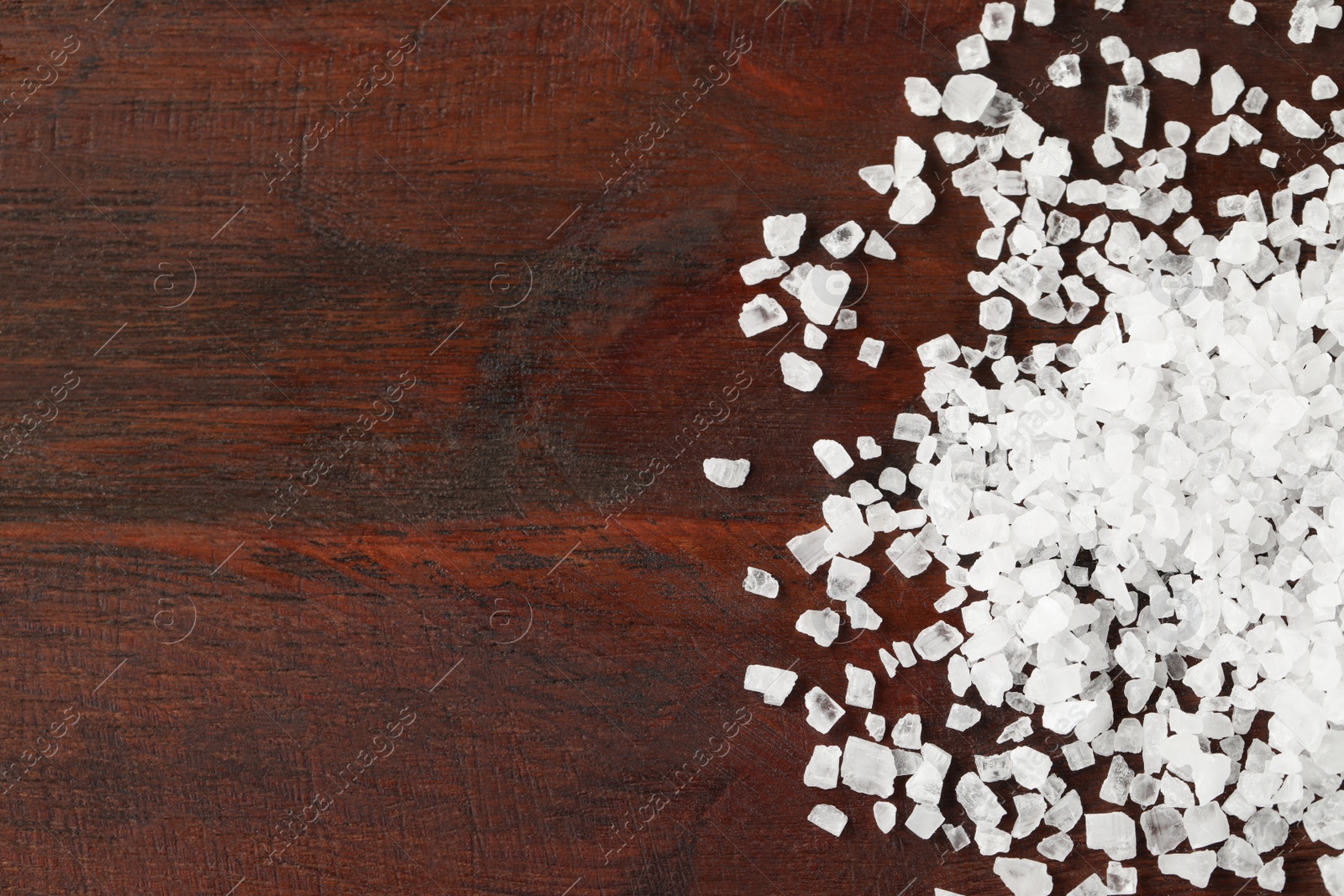 Photo of Natural sea salt on wooden table, flat lay. Space for text