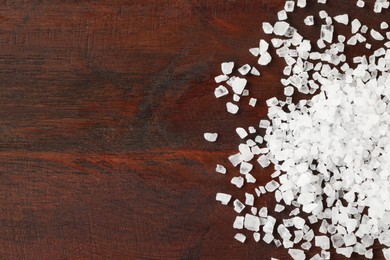 Natural sea salt on wooden table, flat lay. Space for text