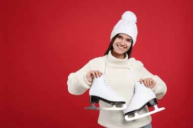 Photo of Happy woman with ice skates on red background