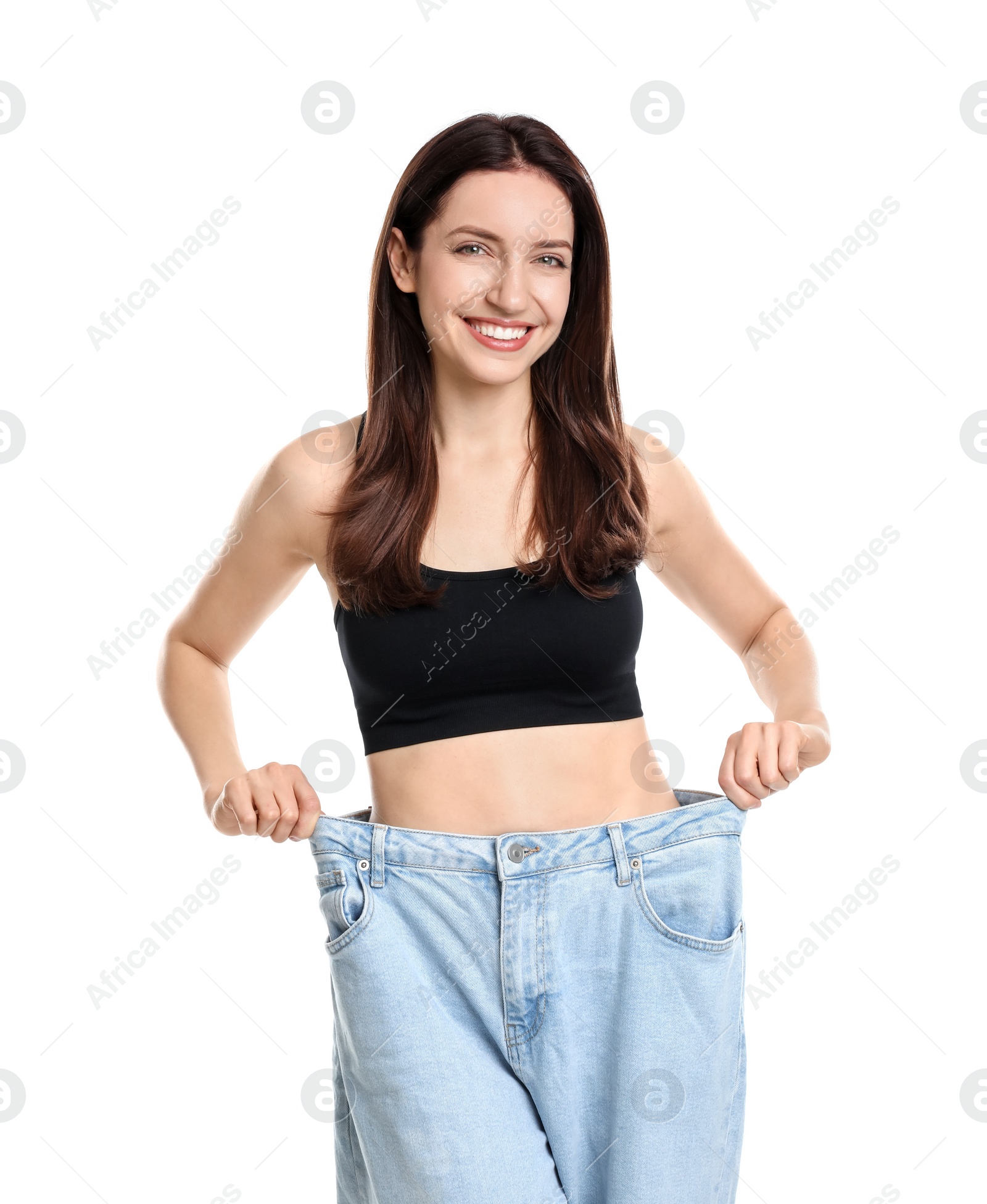 Photo of Happy young woman in big jeans showing her slim body on white background