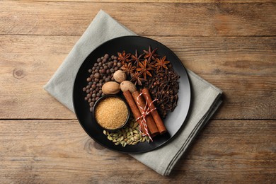 Dishware with different spices on wooden table, top view