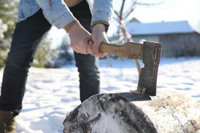 Photo of Man chopping wood with axe outdoors on winter day, closeup
