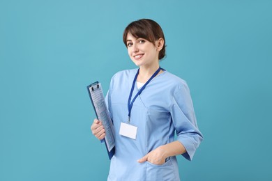 Photo of Portrait of smiling medical assistant with clipboard on light blue background