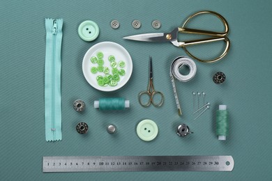 Photo of Flat lay composition with different sewing supplies on green fabric