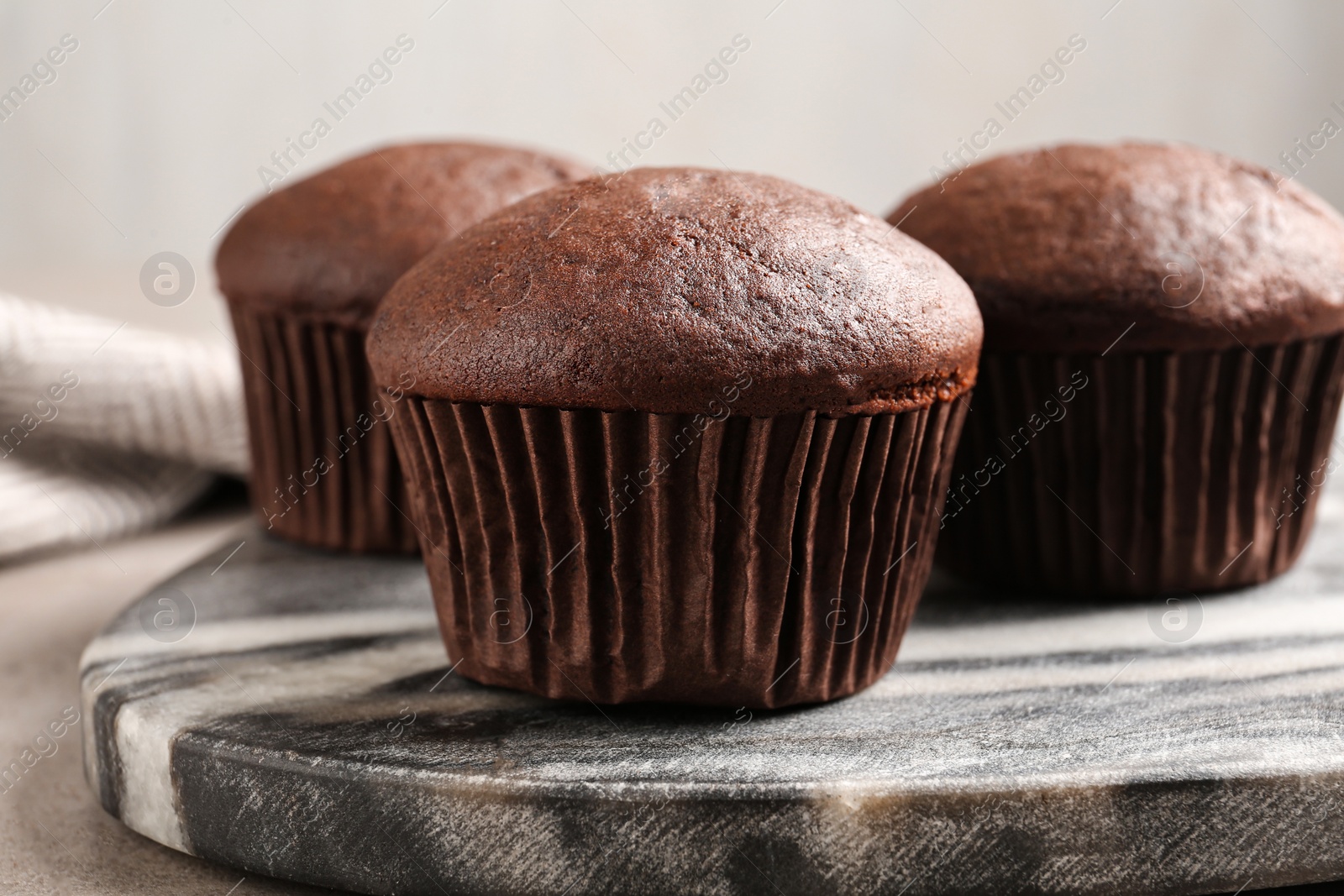 Photo of Delicious fresh chocolate cupcakes on grey marble board, closeup