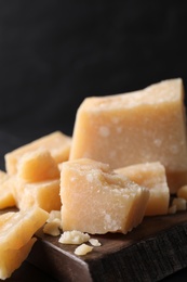 Photo of Pieces of delicious parmesan cheese on wooden board, closeup