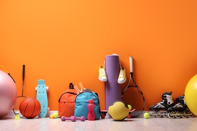 Many different sports equipment near orange wall indoors