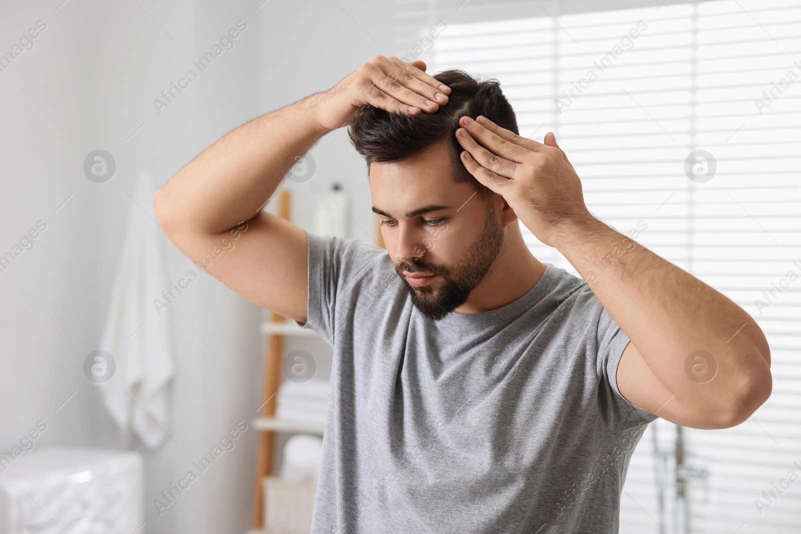 Photo of Man examining his head in bathroom. Dandruff problem