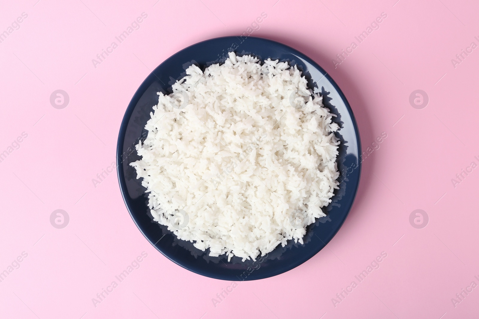 Photo of Plate of boiled rice on color background, top view