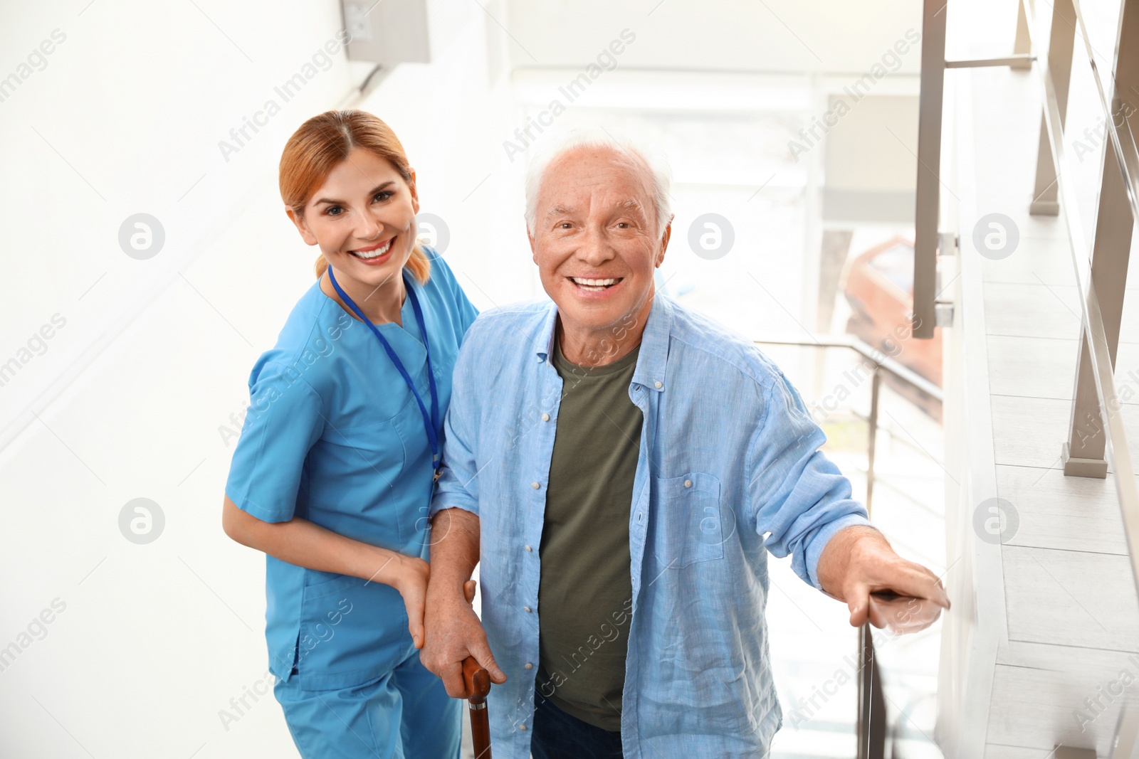 Photo of Nurse assisting elderly man on stairs indoors