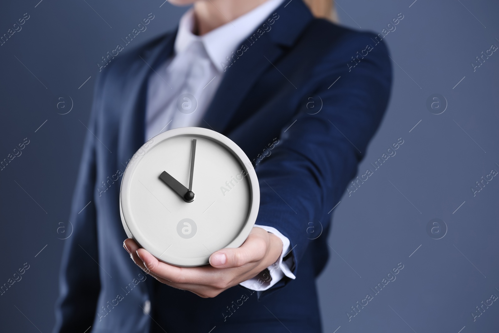 Photo of Businesswoman holding alarm clock on color background. Time concept