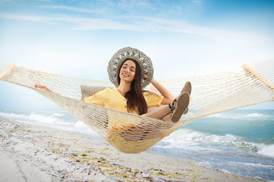 Woman resting in hammock near sea on sunny day 