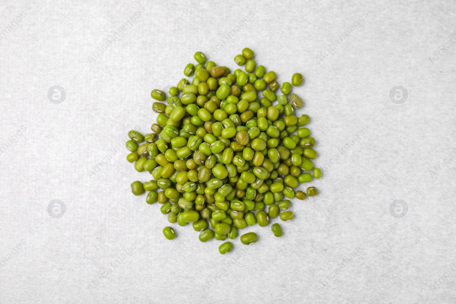 Photo of Pile of green mung beans on light grey table, top view