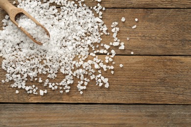 Natural sea salt and scoop on wooden table, flat lay. Space for text