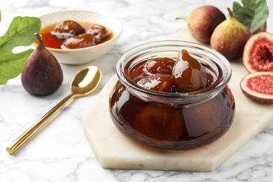 Photo of Jar of tasty sweet jam and fresh figs on white marble table