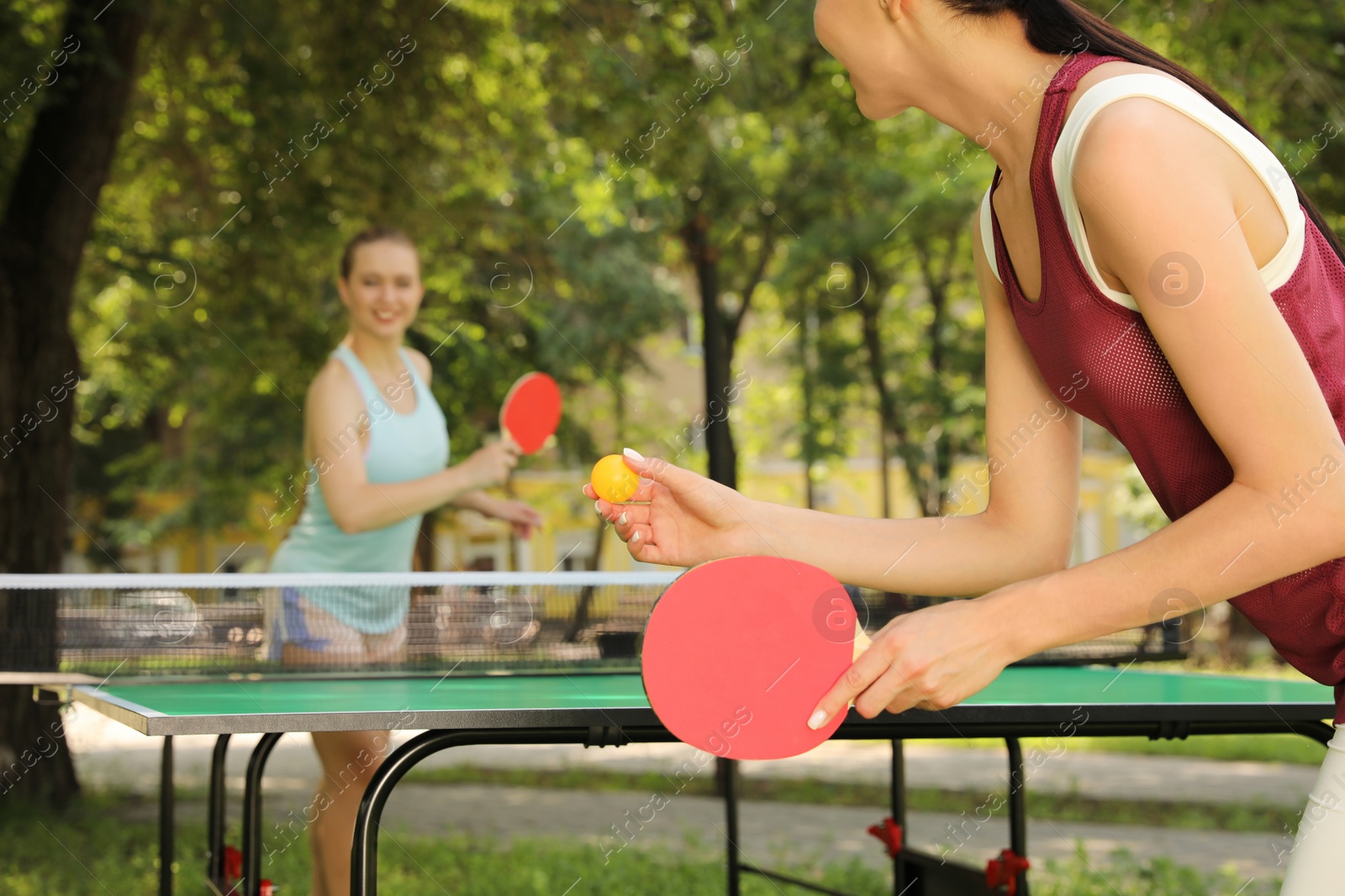 Photo of Young women playing ping pong in park, closeup