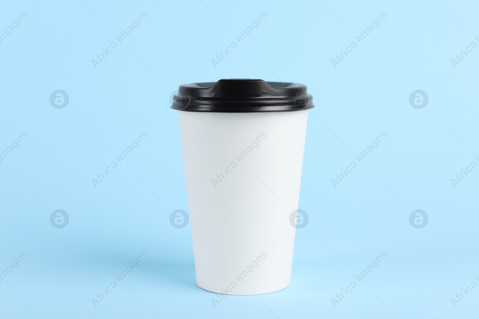 Photo of Paper cup with plastic lid on light blue background. Coffee to go