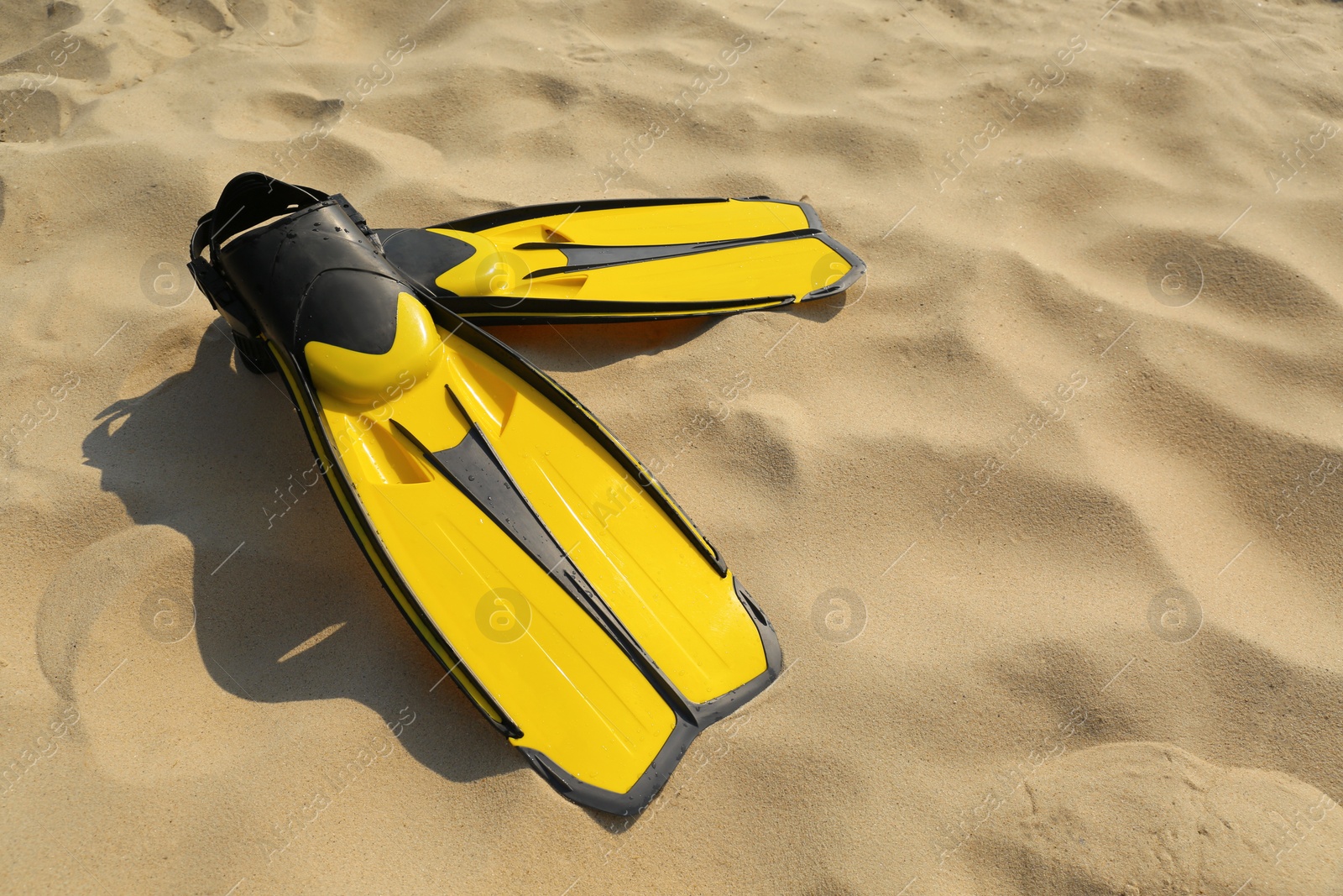 Photo of Pair of yellow flippers on sand. Space for text