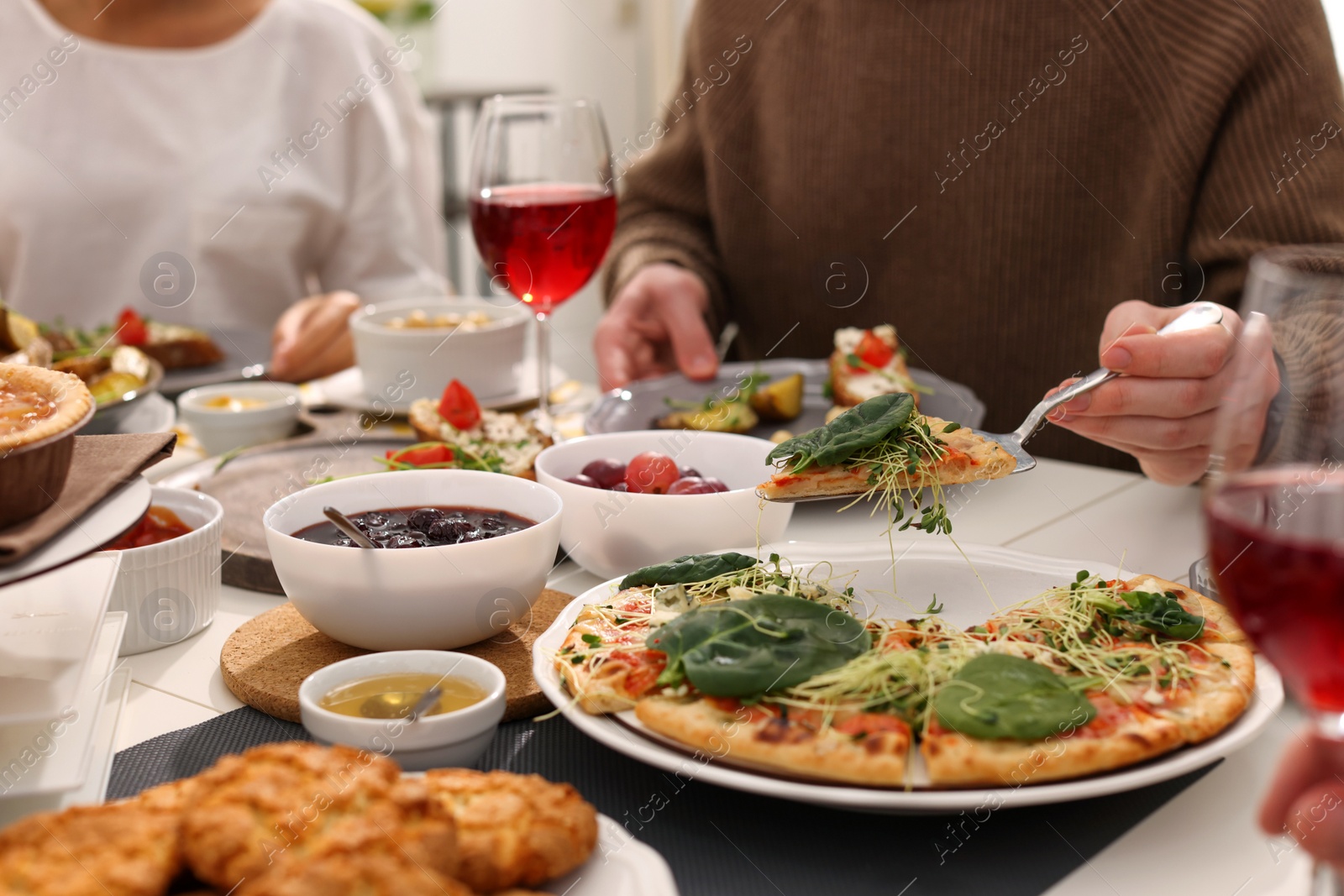 Photo of Man taking slice of pizza during brunch at table indoors, closeup