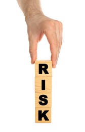 Photo of Man stacking wooden cubes with word Risk on white background, closeup