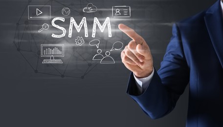 Social media marketing concept. Man touching virtual icon SMM against dark background, closeup