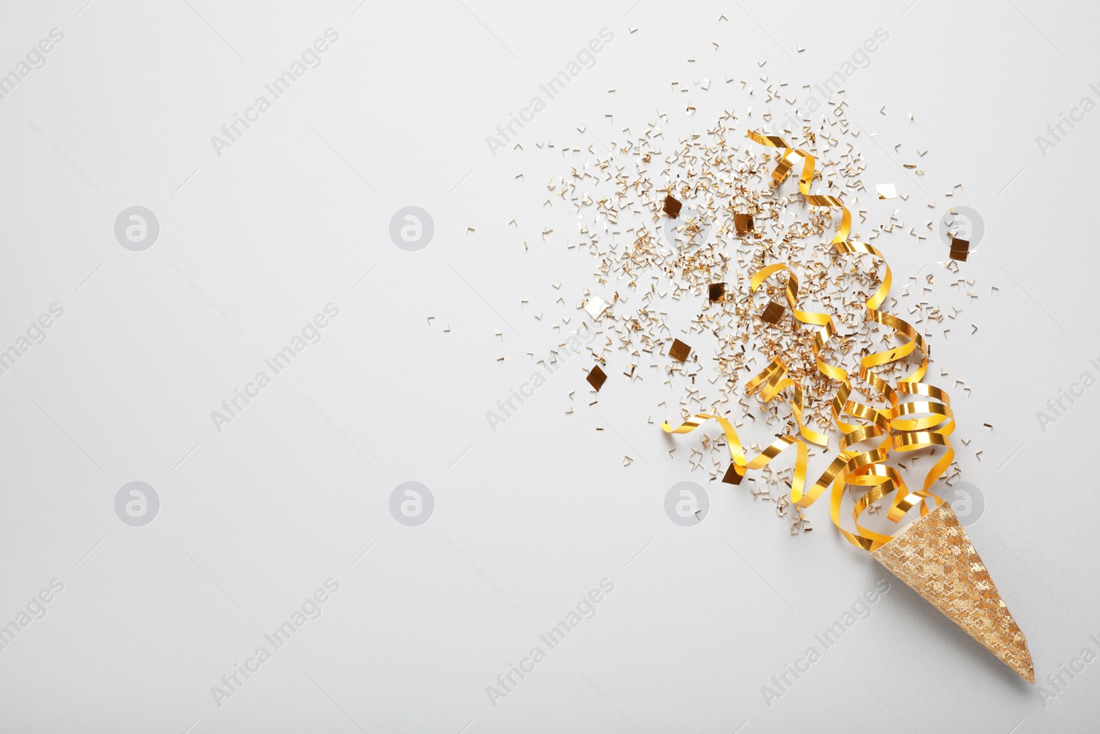 Photo of Golden confetti and streamers with party cracker on white background, top view. Space for text