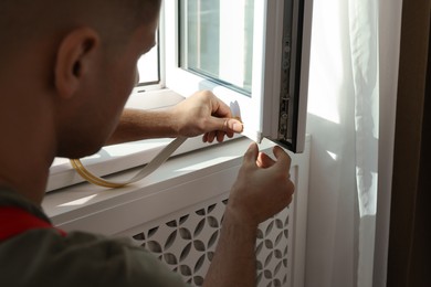 Photo of Man putting rubber draught strip onto window, closeup
