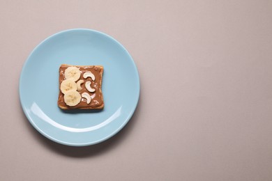 Toast with tasty nut butter, banana slices and cashews on light grey background, top view. Space for text