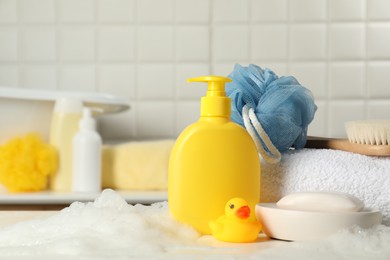 Baby cosmetic products, bath duck, brush and towel on white table