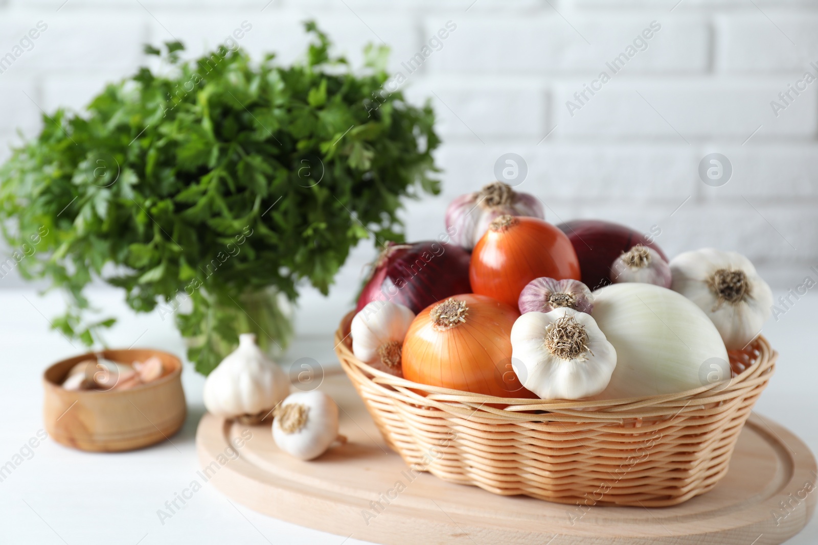 Photo of Fresh raw garlic, onions and parsley on white table