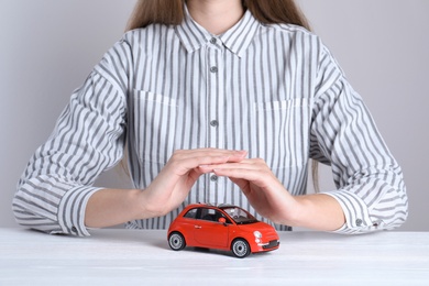 Photo of Insurance agent covering toy car on table, closeup