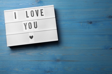 Lightbox with phrase I Love You on blue wooden background, top view. Space for text