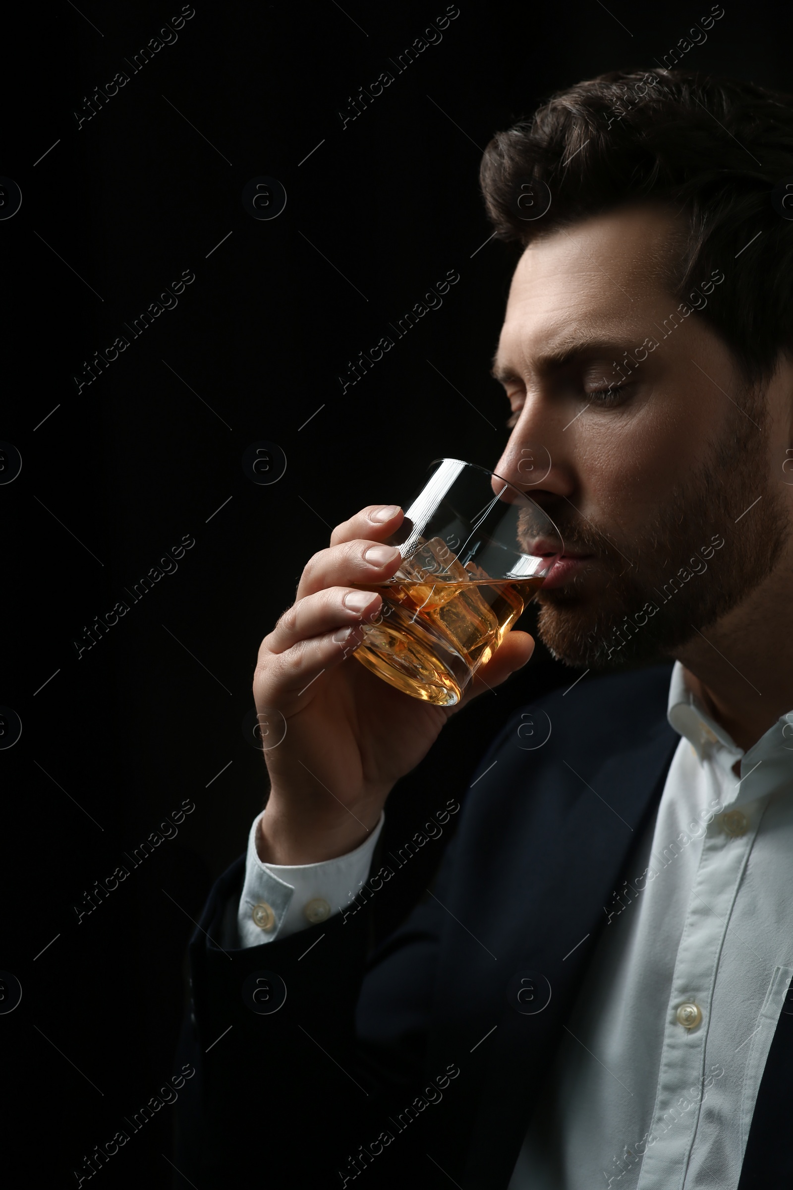 Photo of Man in suit drinking whiskey on black background