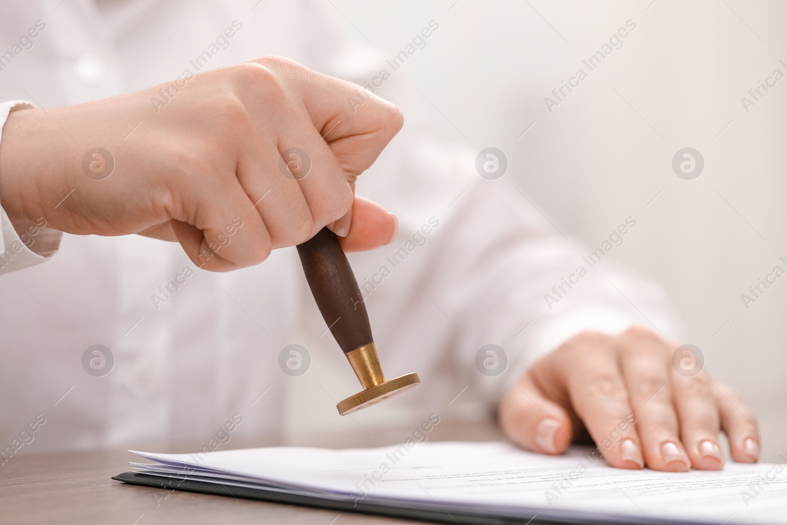 Photo of Woman stamping document at table, closeup view