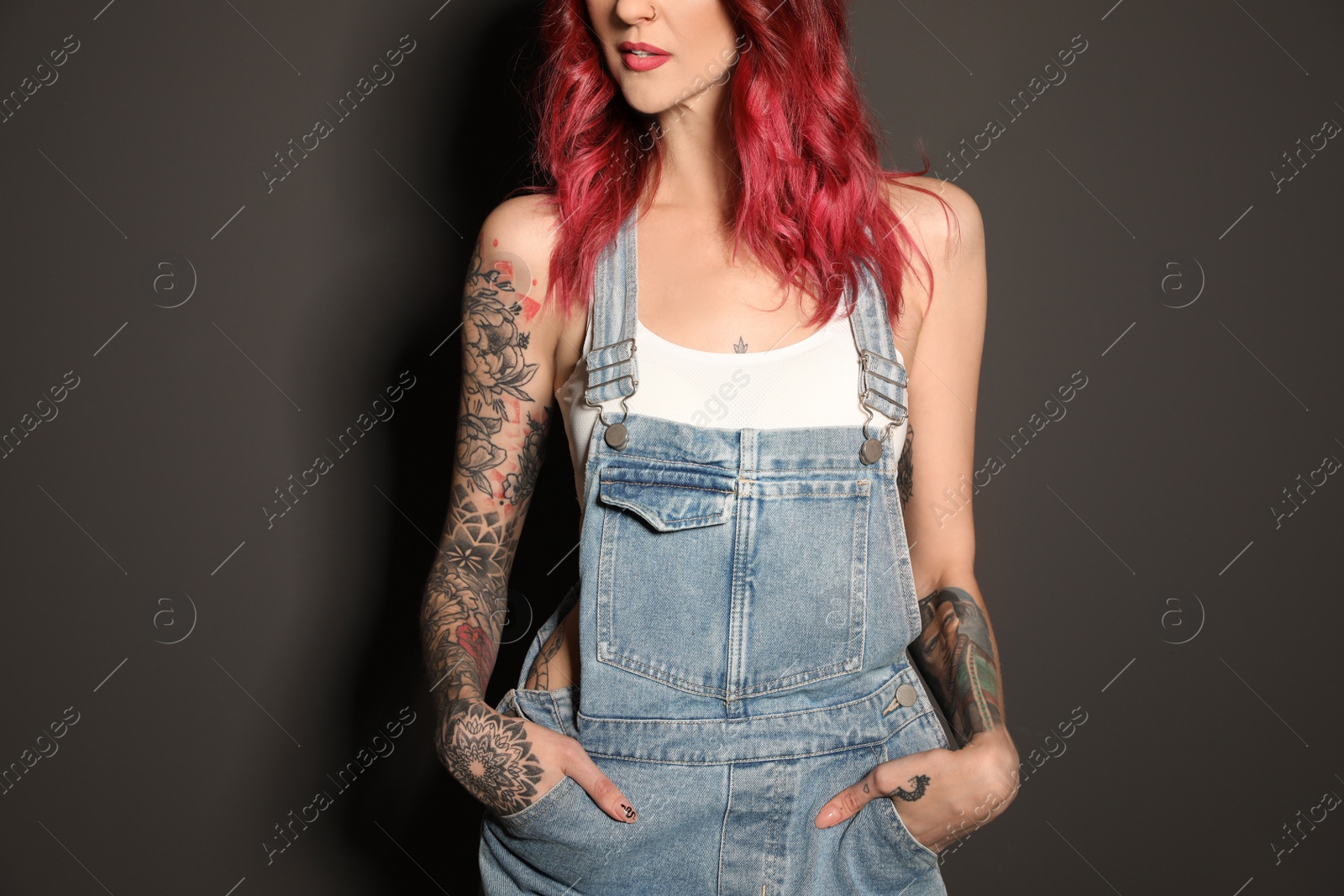 Photo of Beautiful woman with tattoos on body against black background, closeup