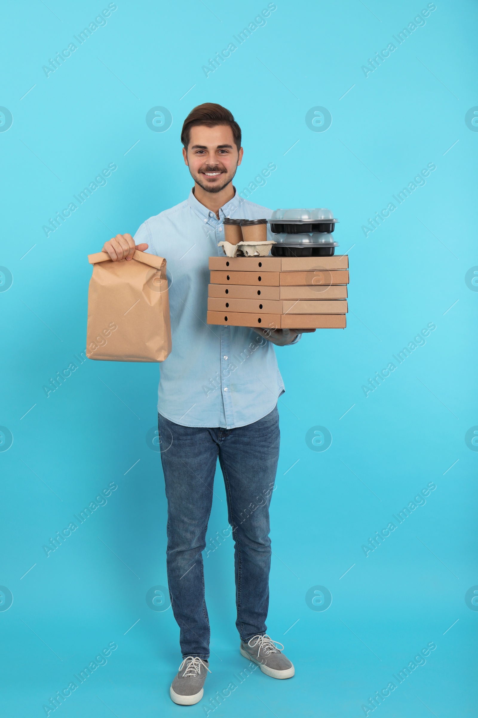 Photo of Young courier with different orders on color background. Food delivery service