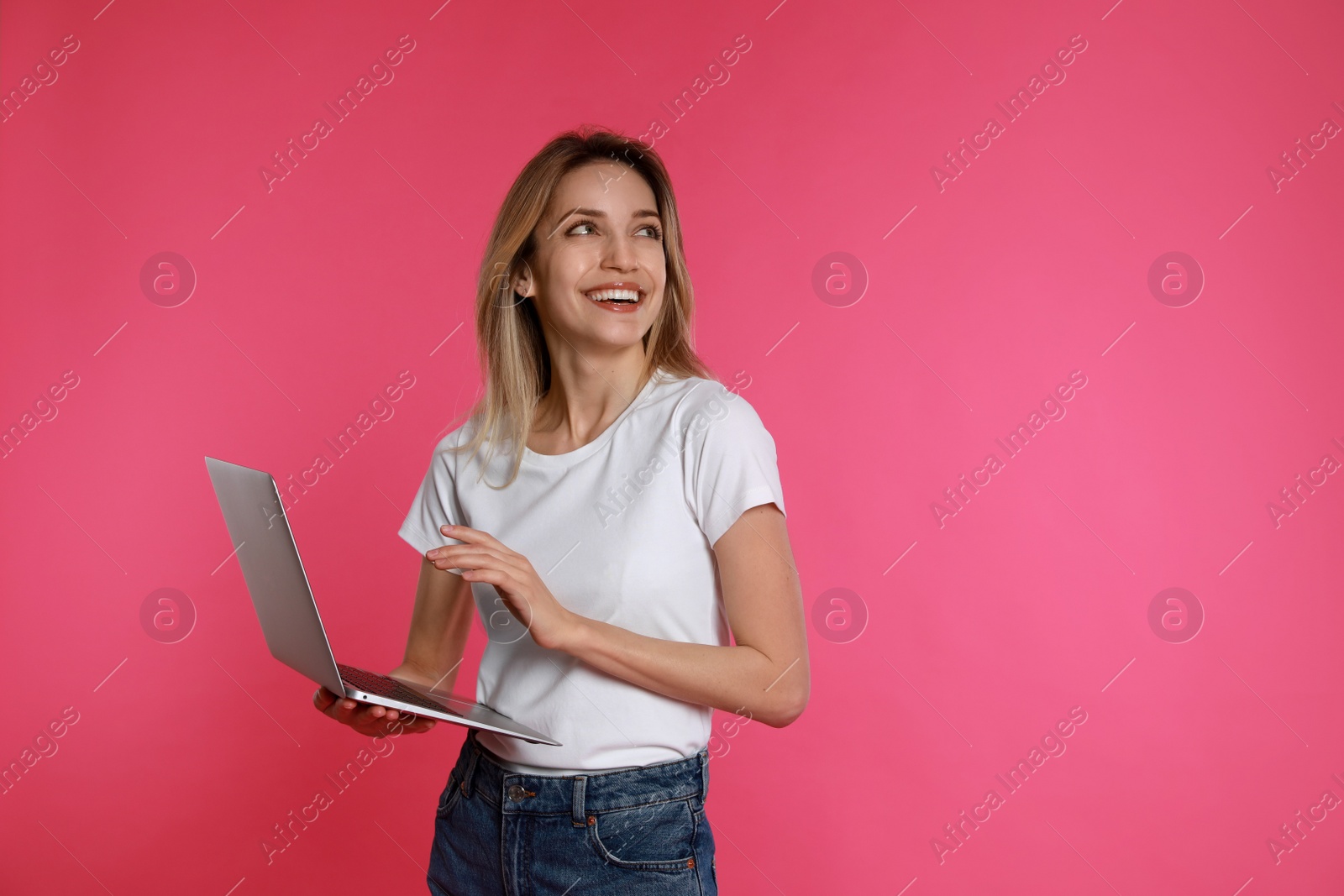 Photo of Young woman with modern laptop on pink background