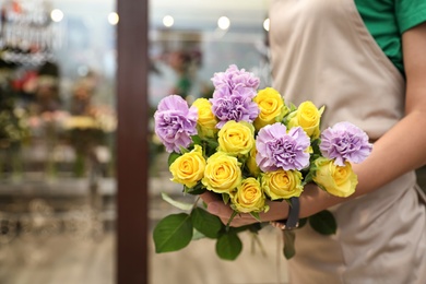 Photo of Female florist holding beautiful bouquet in flower shop, closeup