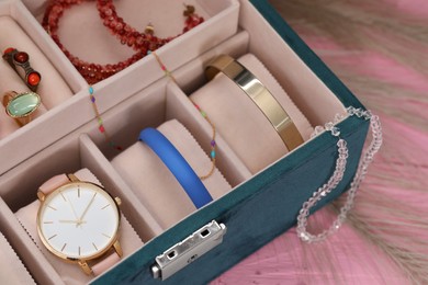 Photo of Jewelry box with many different accessories on pink wooden table, closeup