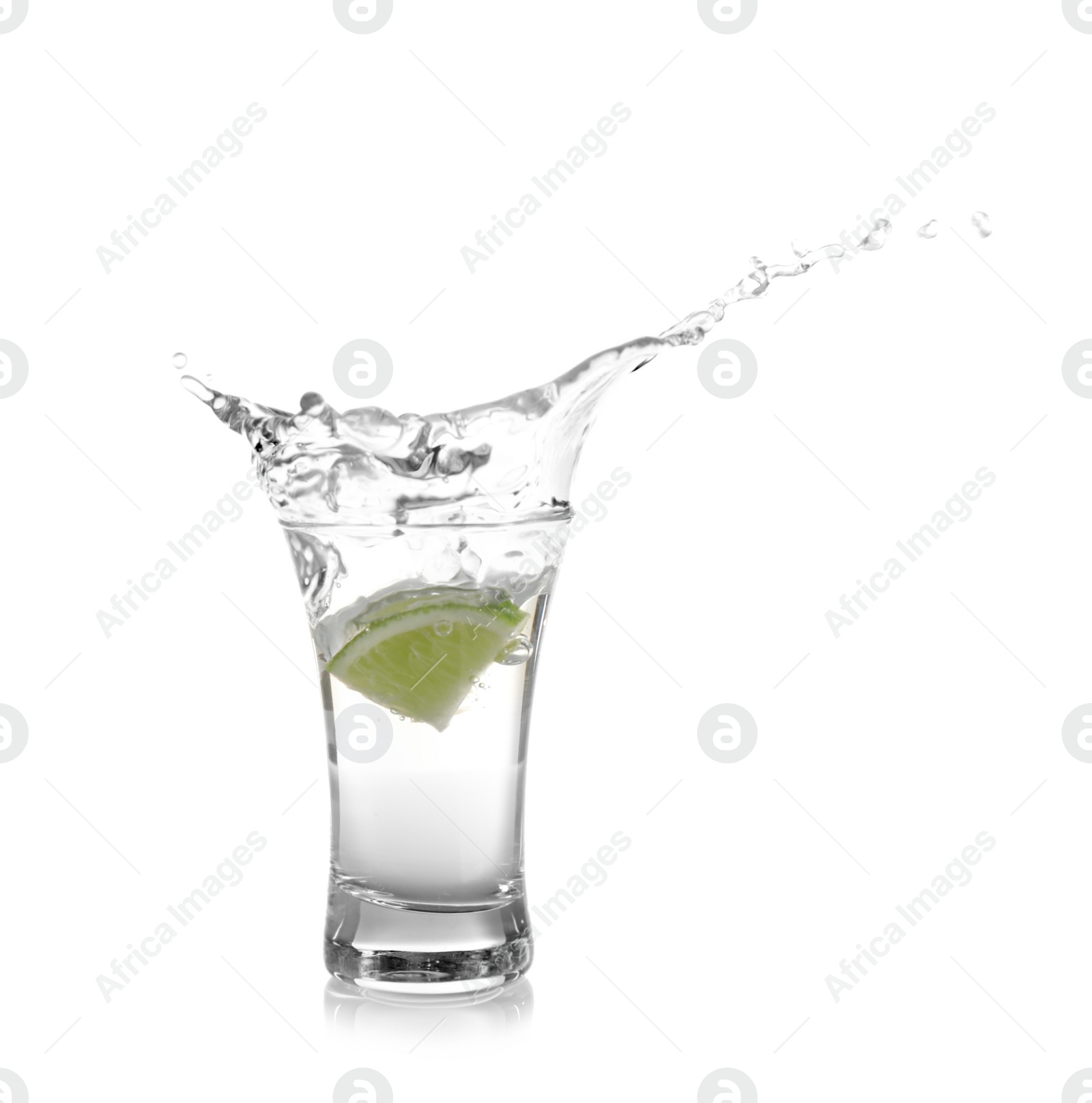 Photo of Splashing Mexican Tequila in shot glass with lime slice isolated on white