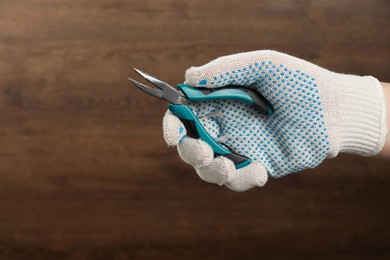 Photo of Man with bent nose pliers on wooden background, closeup. Space for text